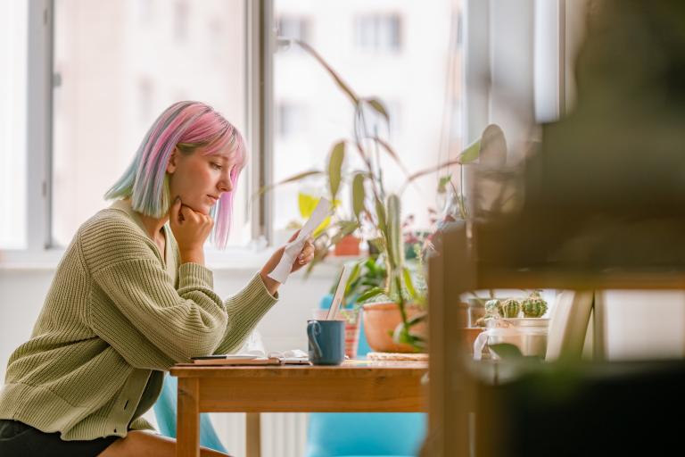 Jonge vrouw aan tafel met smartphone