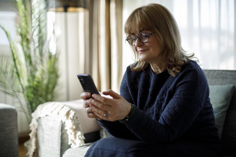 Vrouw met telefoon in woonkamer