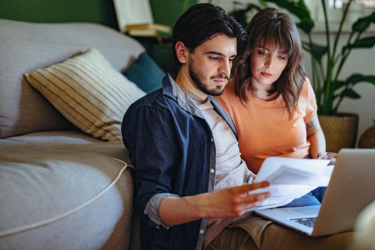 Man en vrouw lezen brief met laptop op schoot