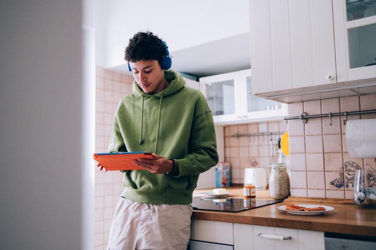 Jonge man staat met tablet in keuken