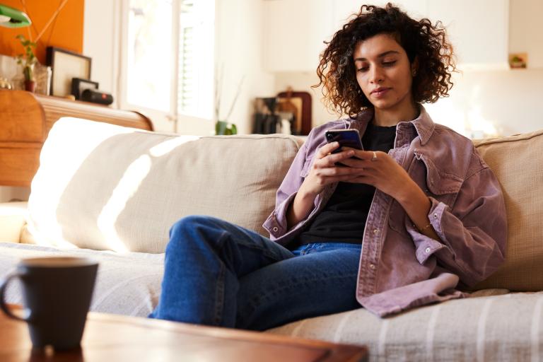Vrouw zit thuis op de bank met smartphone